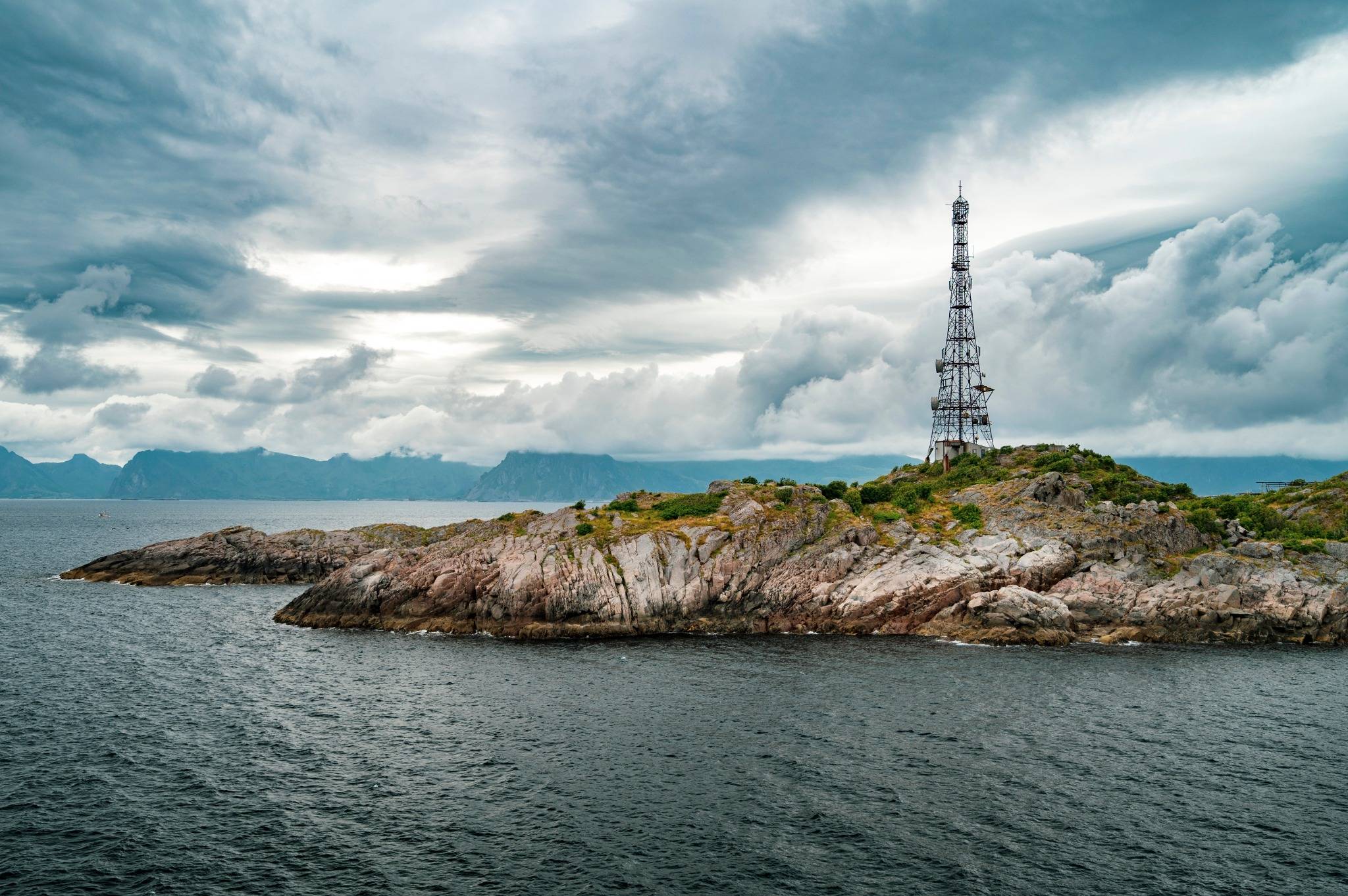 ystlandskap med kommunikasjonstårn på en øy under skyer– vier digital tilkobling, struktur og modernisering. Illustrerer OneCos overgang til skybasert HR- og lønnssystem støttet av Metier.