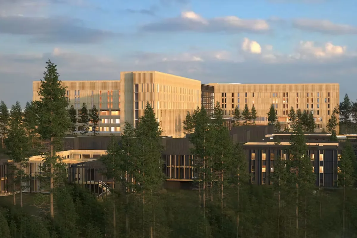 Arkitektillustrasjon av det planlagte Mjøssykehuset i Moelv, med lyse fasader omgitt av skog.
